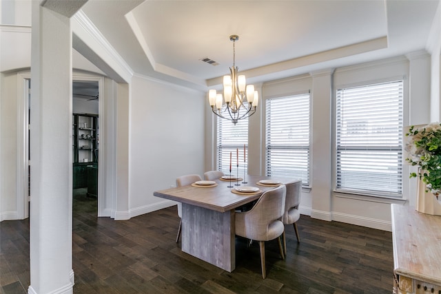 dining room featuring dark hardwood / wood-style floors, a raised ceiling, ornamental molding, and a chandelier