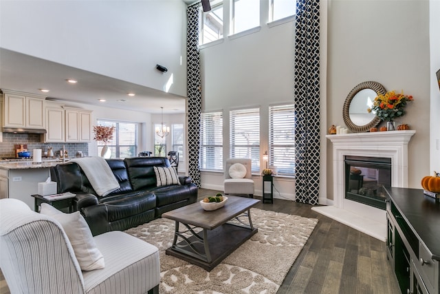 living room with a chandelier, a high ceiling, and dark hardwood / wood-style flooring