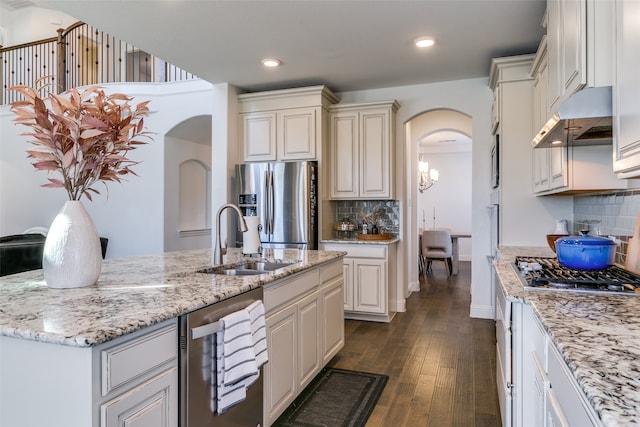 kitchen with a kitchen island with sink, sink, decorative backsplash, appliances with stainless steel finishes, and dark hardwood / wood-style flooring