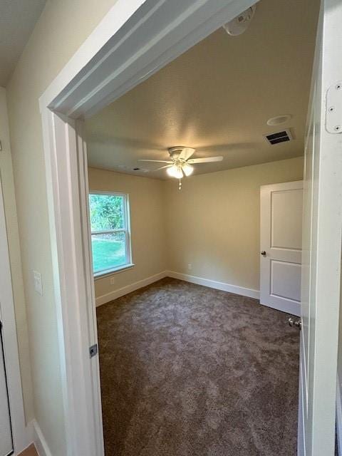 spare room with dark colored carpet and ceiling fan