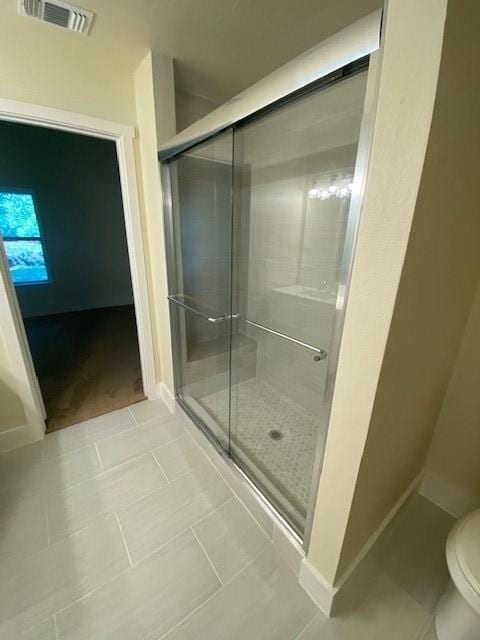 bathroom with tile patterned flooring, toilet, and walk in shower