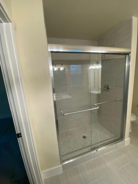 bathroom with tile patterned flooring, toilet, and a shower with door