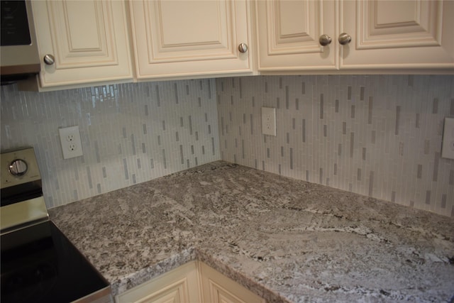 kitchen featuring cream cabinetry, light stone countertops, and stainless steel range with electric cooktop