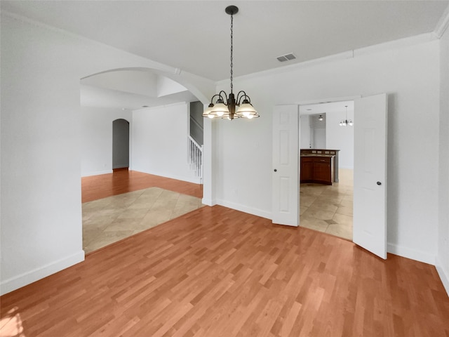 spare room featuring light hardwood / wood-style flooring and a chandelier