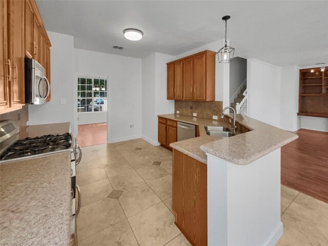 kitchen featuring light hardwood / wood-style flooring, appliances with stainless steel finishes, hanging light fixtures, kitchen peninsula, and sink