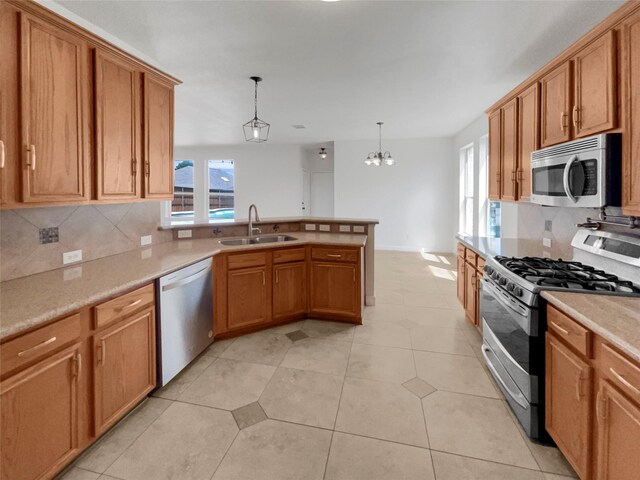 kitchen featuring hanging light fixtures, light tile patterned floors, appliances with stainless steel finishes, sink, and tasteful backsplash