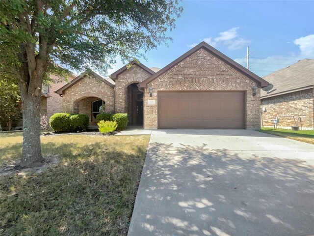 view of front of home featuring an attached garage, concrete driveway, and brick siding