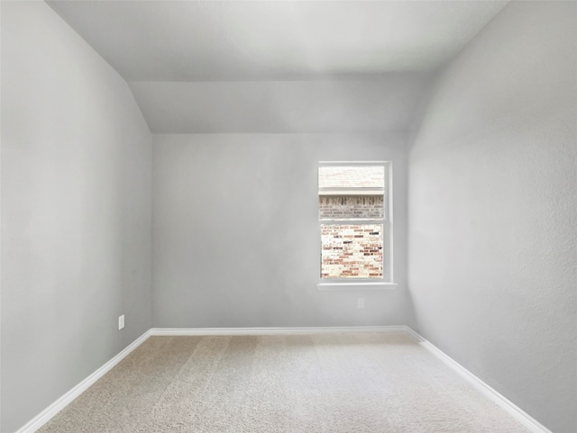 empty room with vaulted ceiling and carpet floors