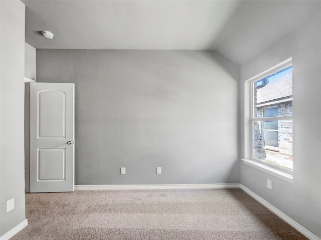 empty room featuring a wealth of natural light, light colored carpet, and lofted ceiling