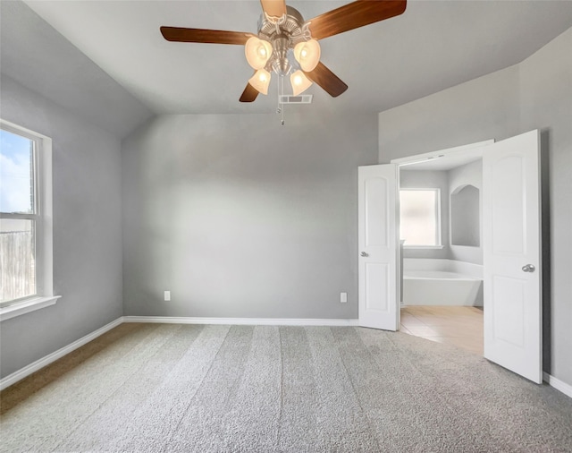 empty room with lofted ceiling, ceiling fan, and light colored carpet