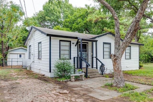 view of front of house with an outdoor structure, fence, and a detached garage