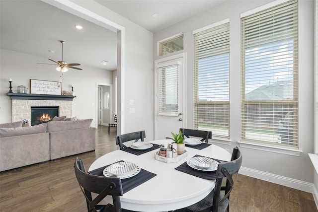 dining space featuring ceiling fan, a fireplace, and dark wood-type flooring