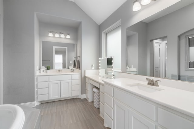 bathroom with vanity, tile patterned flooring, vaulted ceiling, and a bath