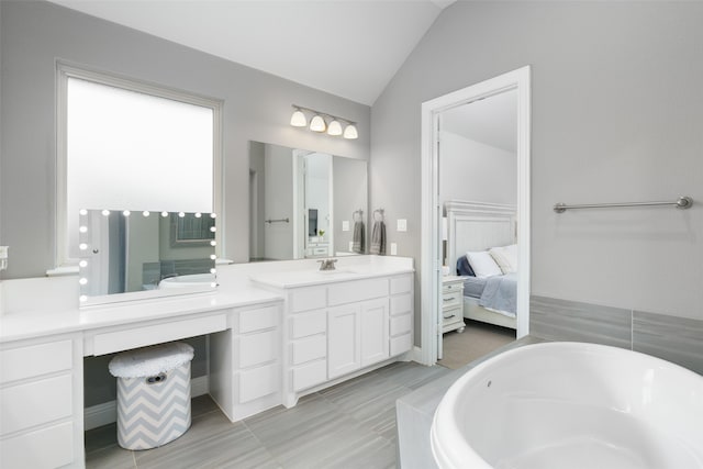 bathroom with lofted ceiling, vanity, and a bathing tub