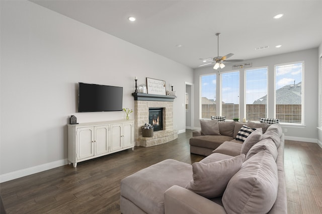 living room featuring ceiling fan, a stone fireplace, and hardwood / wood-style flooring