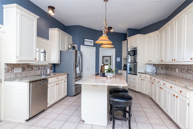 kitchen with a kitchen island, a breakfast bar, stainless steel appliances, sink, and light stone counters