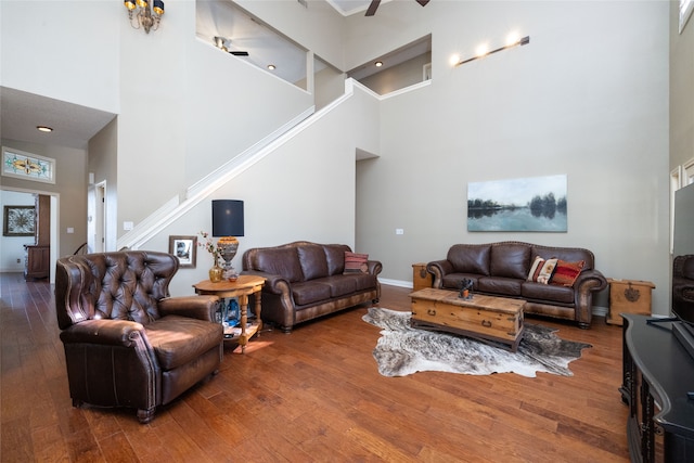 living room with a high ceiling, ceiling fan, and dark wood-type flooring