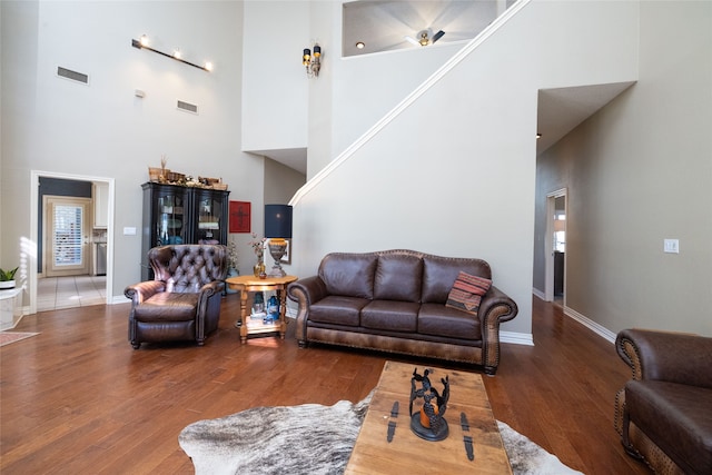 living room featuring a towering ceiling and dark wood-type flooring