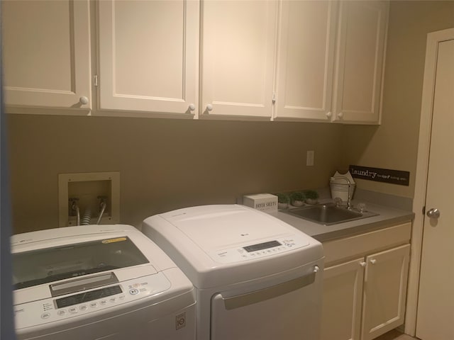 clothes washing area featuring washing machine and clothes dryer, cabinets, and sink