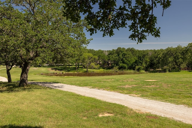 surrounding community with a water view and a lawn