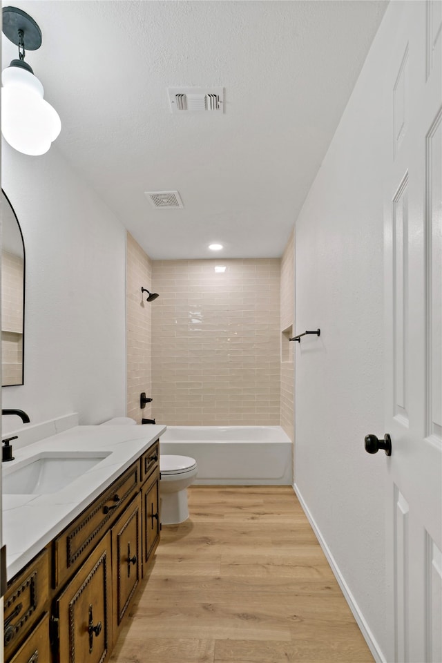 full bathroom featuring tiled shower / bath combo, hardwood / wood-style flooring, vanity, and toilet