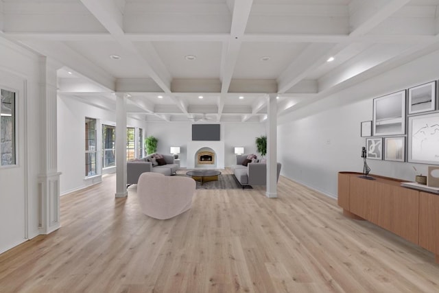 living room featuring decorative columns, beamed ceiling, and light hardwood / wood-style flooring