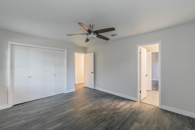 unfurnished bedroom featuring ceiling fan, dark wood-type flooring, connected bathroom, and a closet