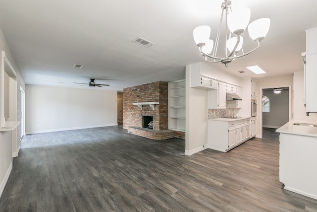 kitchen with ceiling fan with notable chandelier, backsplash, white cabinets, and a fireplace