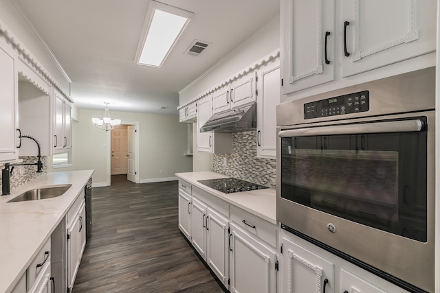 kitchen featuring light stone countertops, white cabinets, black appliances, decorative light fixtures, and sink