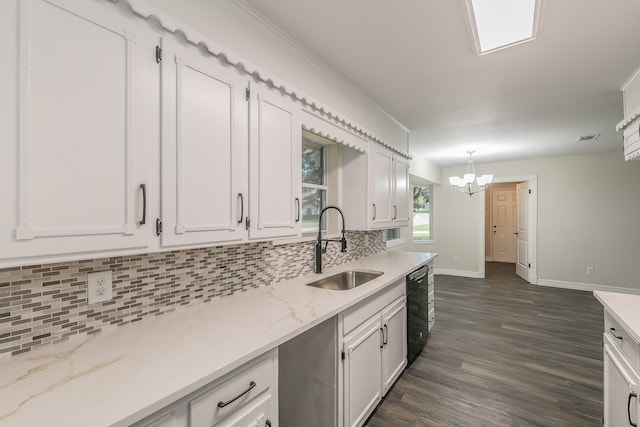 kitchen with pendant lighting, sink, white cabinets, light stone countertops, and black dishwasher