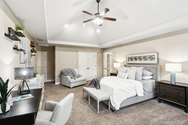 carpeted bedroom featuring ceiling fan, vaulted ceiling, and a tray ceiling