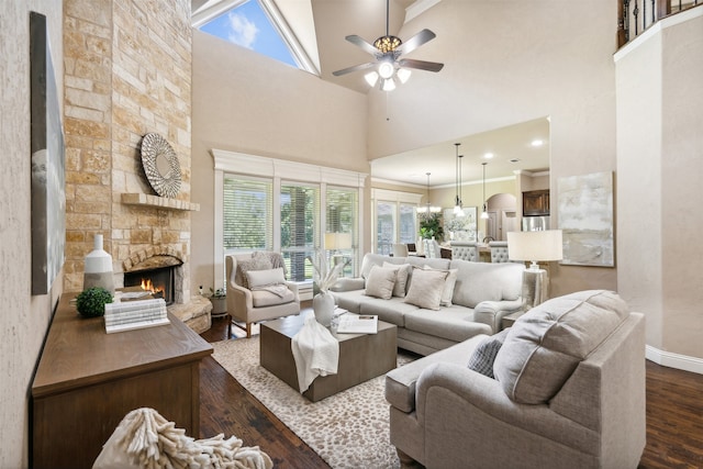 living room with a stone fireplace, dark hardwood / wood-style floors, a towering ceiling, ornamental molding, and ceiling fan