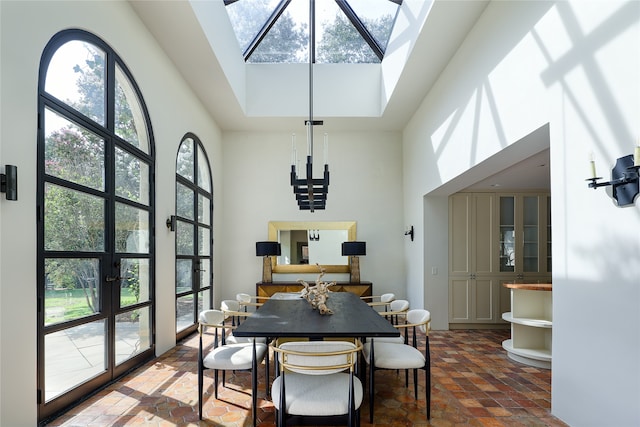 dining space featuring a towering ceiling, plenty of natural light, and a skylight