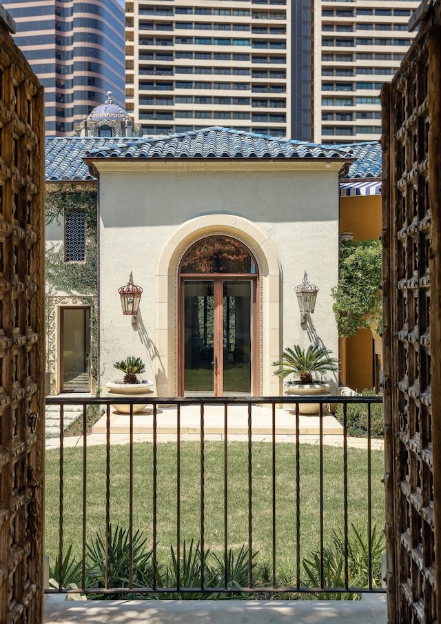 view of exterior entry featuring a lawn and french doors