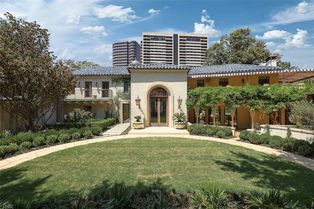 view of front of house featuring a balcony, french doors, and a front yard