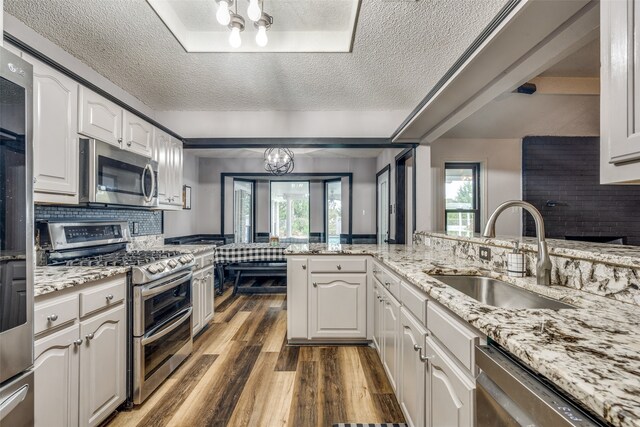 kitchen featuring a textured ceiling, a notable chandelier, appliances with stainless steel finishes, sink, and white cabinetry