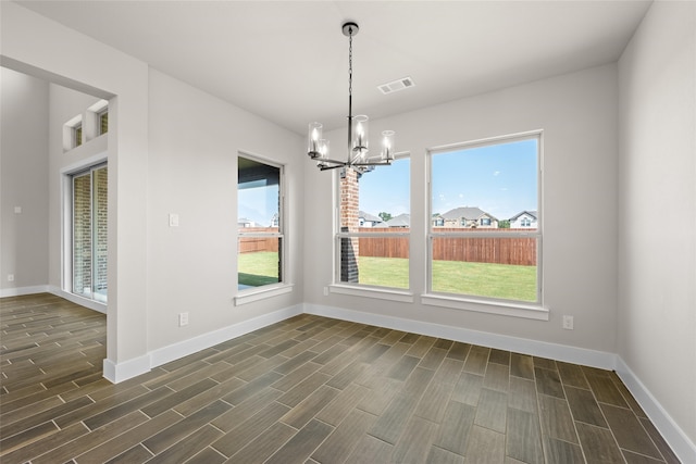 unfurnished dining area with an inviting chandelier and dark hardwood / wood-style flooring