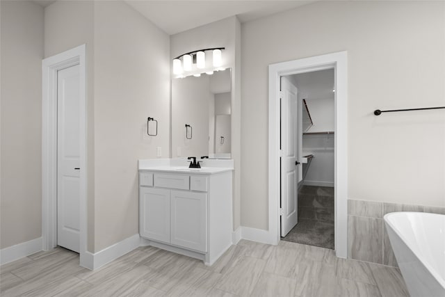 bathroom featuring tiled tub and vanity