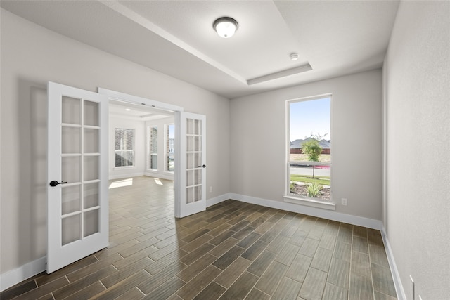 unfurnished room featuring french doors and a raised ceiling