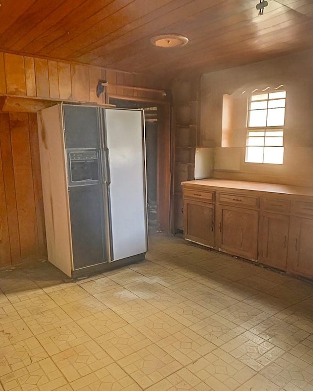 kitchen with fridge with ice dispenser, wood ceiling, and wooden walls