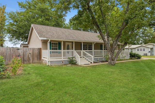 ranch-style home with covered porch, a shingled roof, fence, and a front lawn