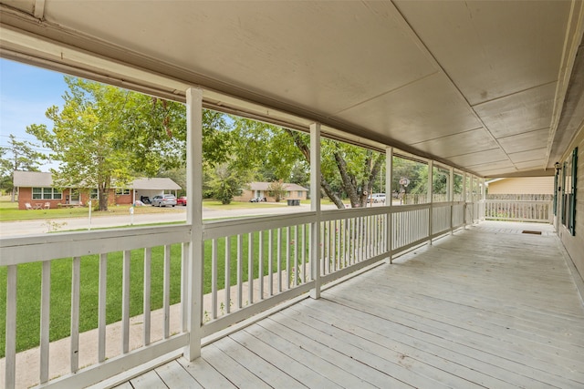 wooden terrace with a lawn and covered porch