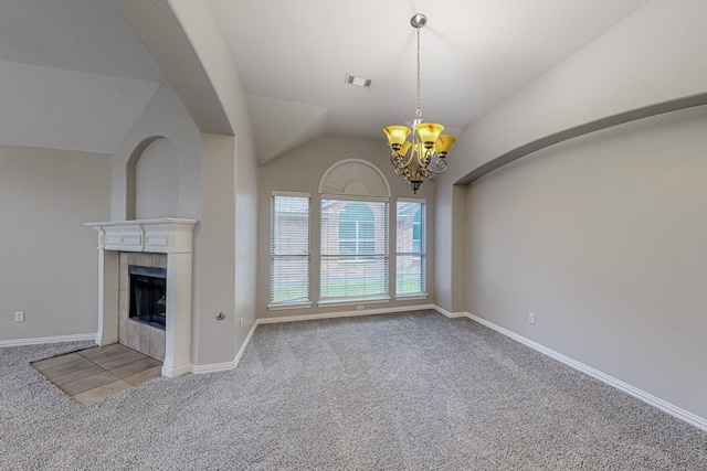 unfurnished living room featuring light colored carpet, vaulted ceiling, an inviting chandelier, and a tiled fireplace