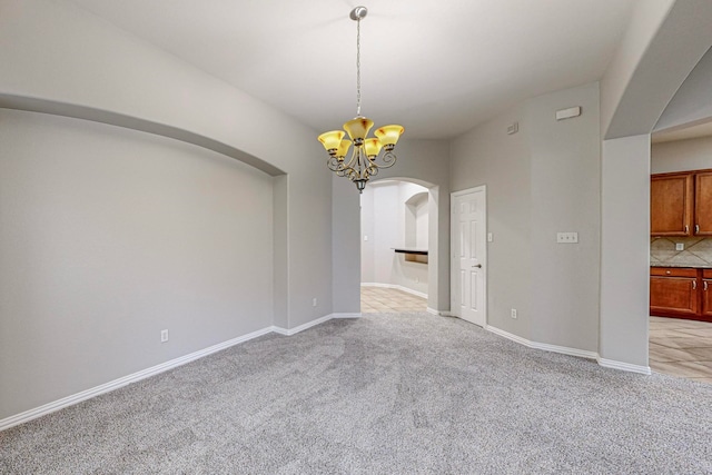 unfurnished dining area featuring light carpet and an inviting chandelier