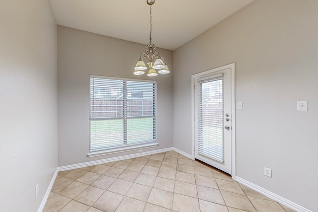 spare room featuring a chandelier and light tile patterned flooring