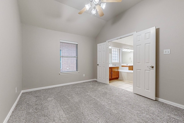 unfurnished bedroom featuring ceiling fan, vaulted ceiling, ensuite bathroom, and light colored carpet