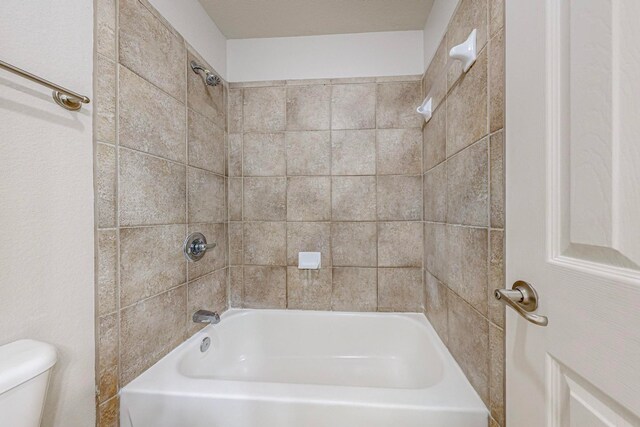 bathroom with toilet and tiled shower / bath combo