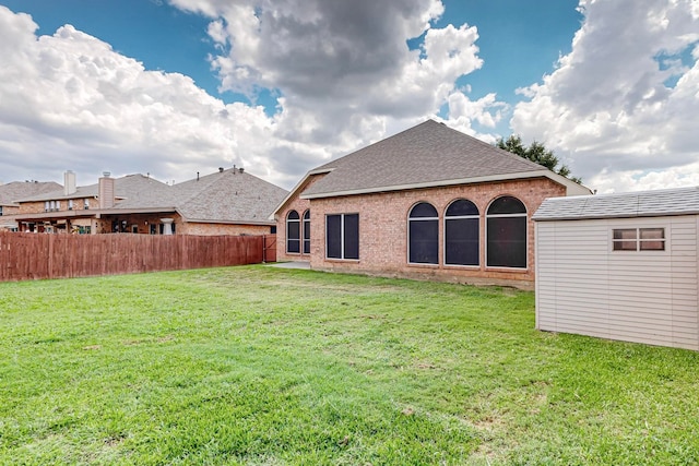 rear view of property featuring a yard and a shed