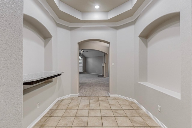 corridor featuring a raised ceiling and light tile patterned floors