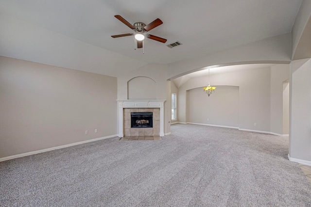 unfurnished living room featuring ceiling fan with notable chandelier, a tile fireplace, light carpet, and vaulted ceiling